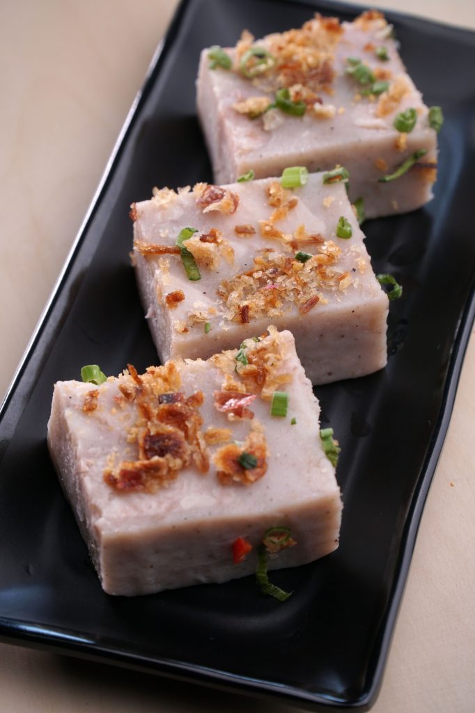 Vertical closeup of taro cakes served on a black plate