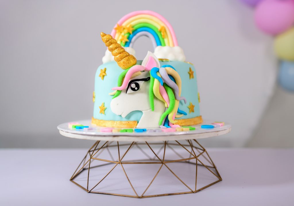 Beautiful unicorn-themed baby girls birthday cake on a stand.