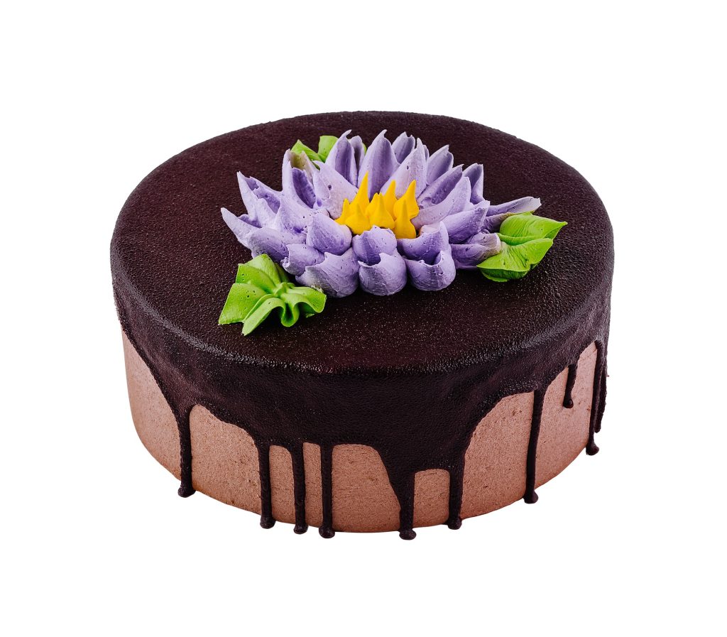 Chocolate cake dripping with chocolate icing decorated with buttercream flower