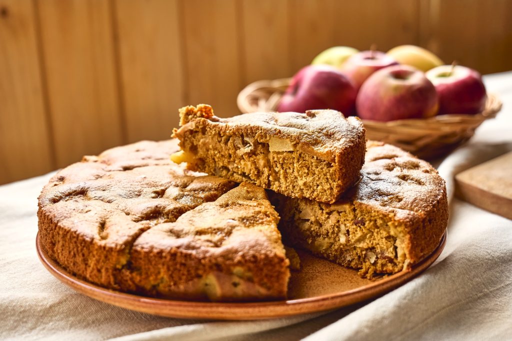 Slice of homemade apple cake Charlotte with walnuts and apples on the table with linen tablecloth.